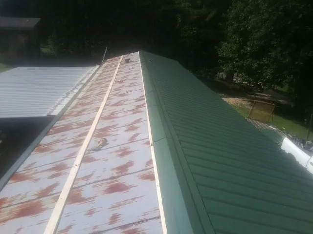 Old rusted panels beside newly installed green metal roofing — Wind Damage Roof Repair by Roofing Brothers in Westerville