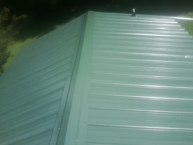 New green metal panels meeting at the ridge of a roof — Flat Roof Repair work by our crew in Westerville