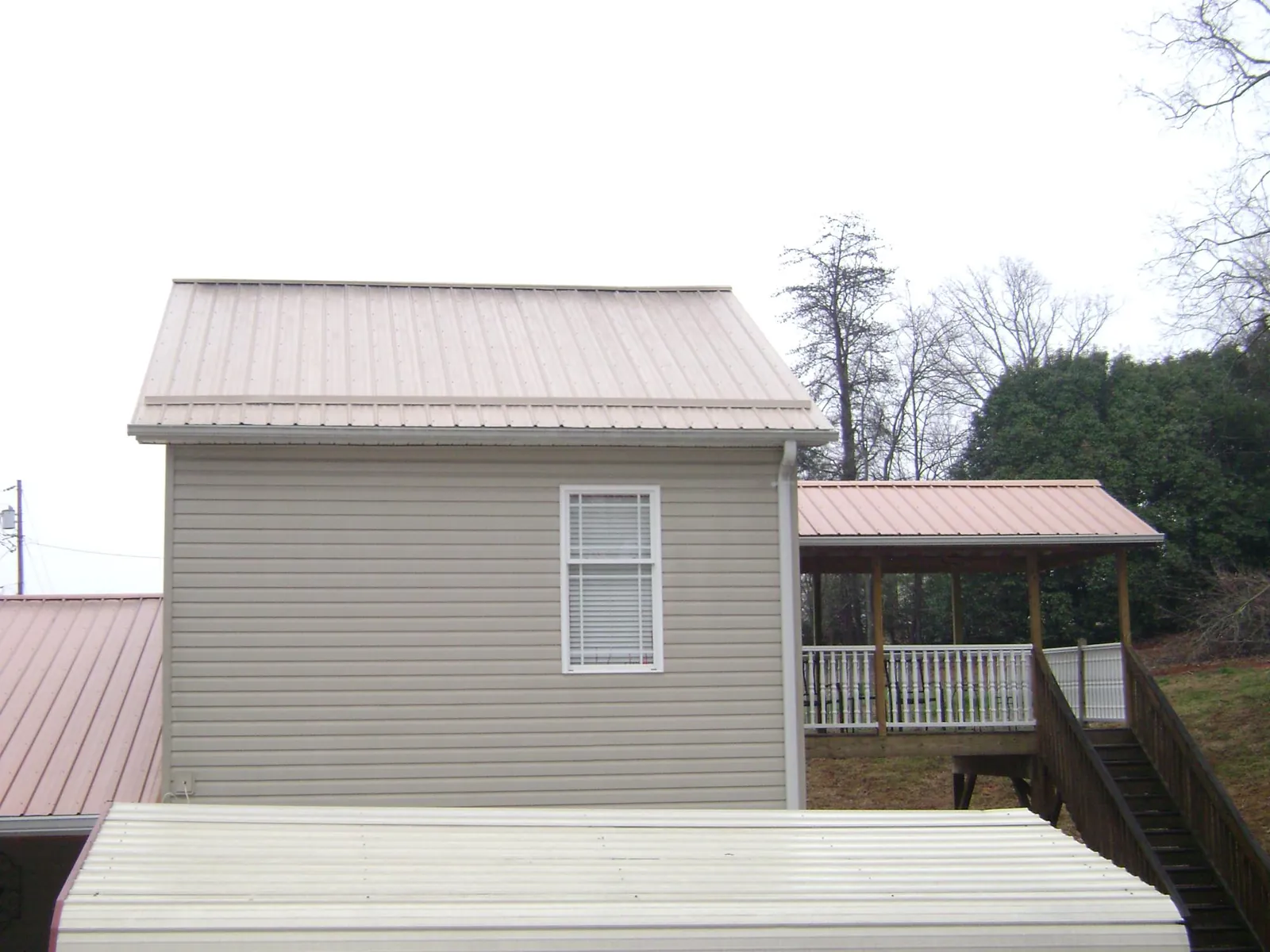 Tan metal roofs on a two story addition and attached porch, from a Roof Replacement job in Westerville