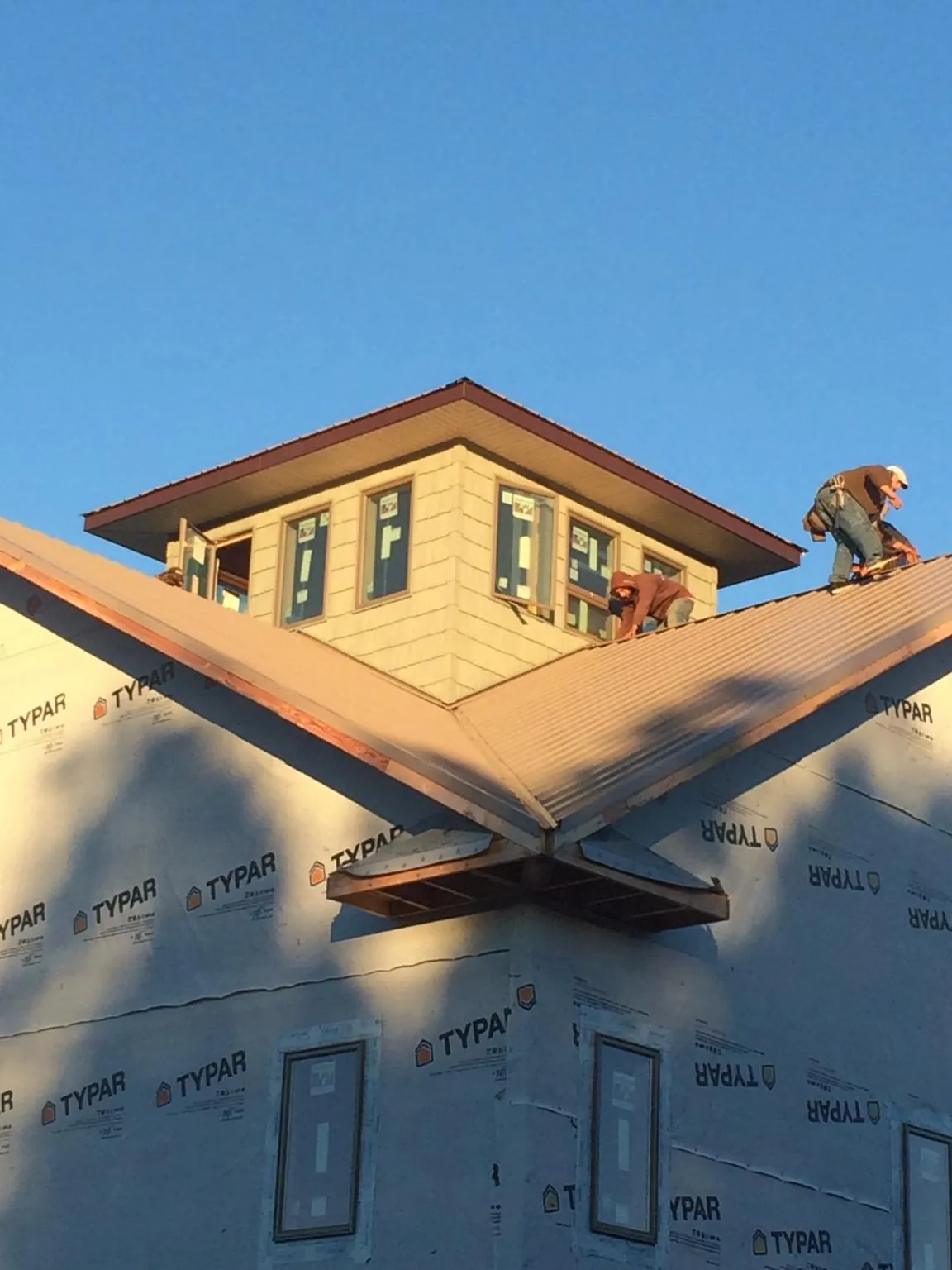Roofers working around a rooftop cupola on a new metal roof at sunset — Roof Waterproofing in Westerville by Roofing Brothers